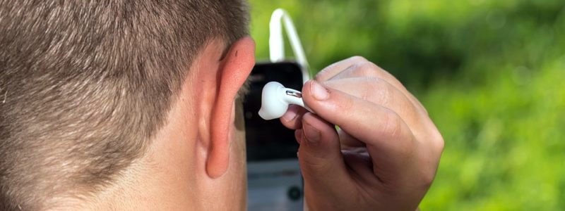 Mies laittaa nappikuuloketta korvaansa.