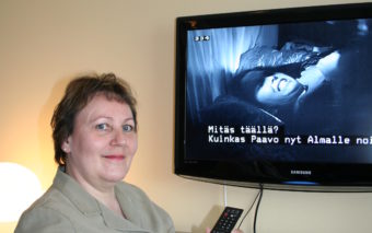 Nainen katsoo televisiotekstitettyä ohjelmaa.