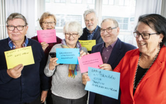 Kuusi henkilöä näyttävät paperilappuja, johon he ovat kirjoittaneet asioita, joita he haluavat oppia tekemään älylaitteillaan paremmin. Esim. valokuvan lähettäminen ja tallennus, mobiilipankin käyttöönotto, virustorjunta.