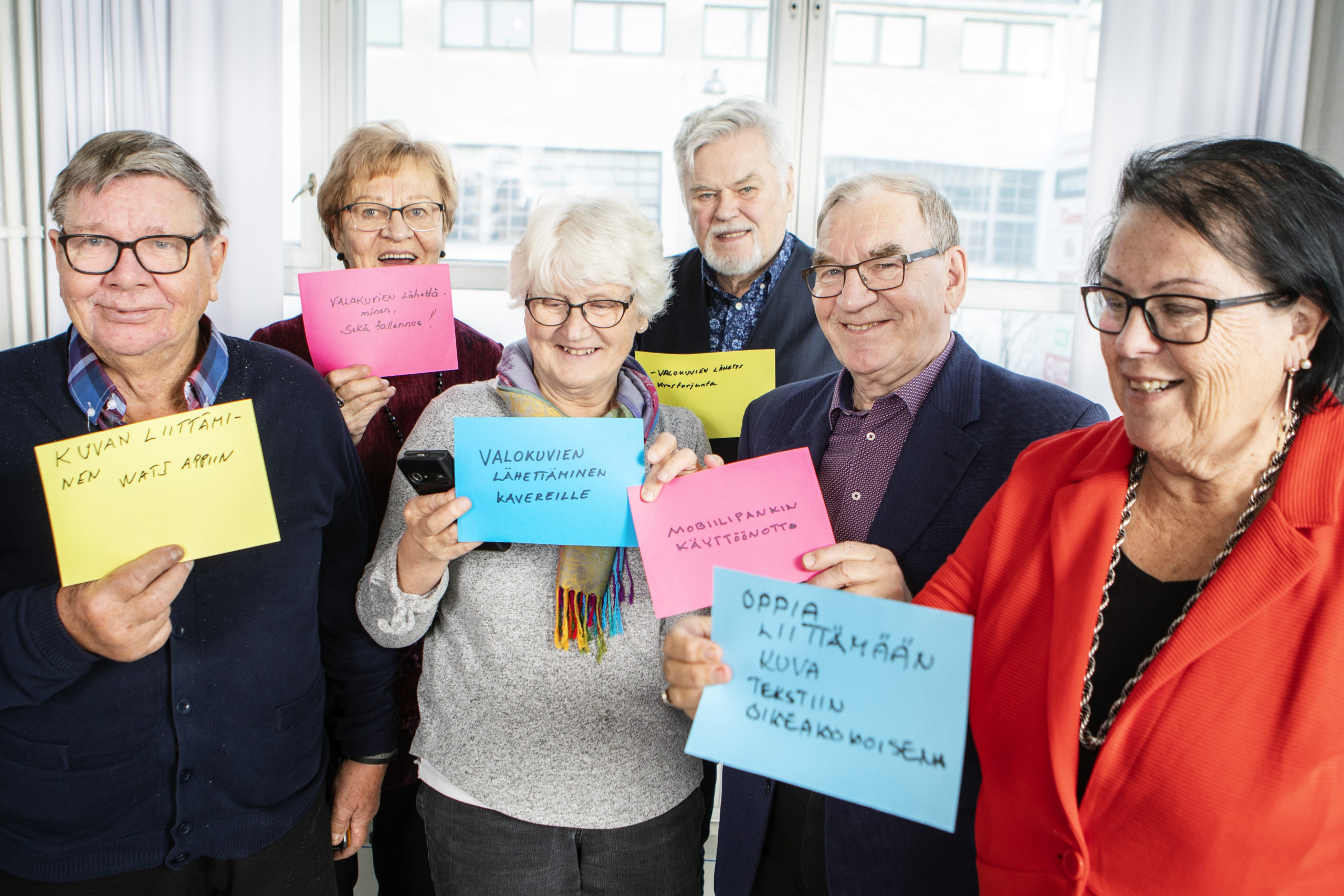 Kuusi henkilöä näyttävät paperilappuja, johon he ovat kirjoittaneet asioita, joita he haluavat oppia tekemään älylaitteillaan paremmin. Esim. valokuvan lähettäminen ja tallennus, mobiilipankin käyttöönotto, virustorjunta.