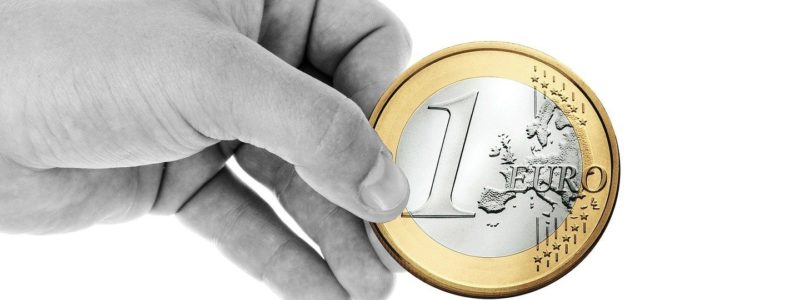 Käsi, jossa on yhden euron kolikko