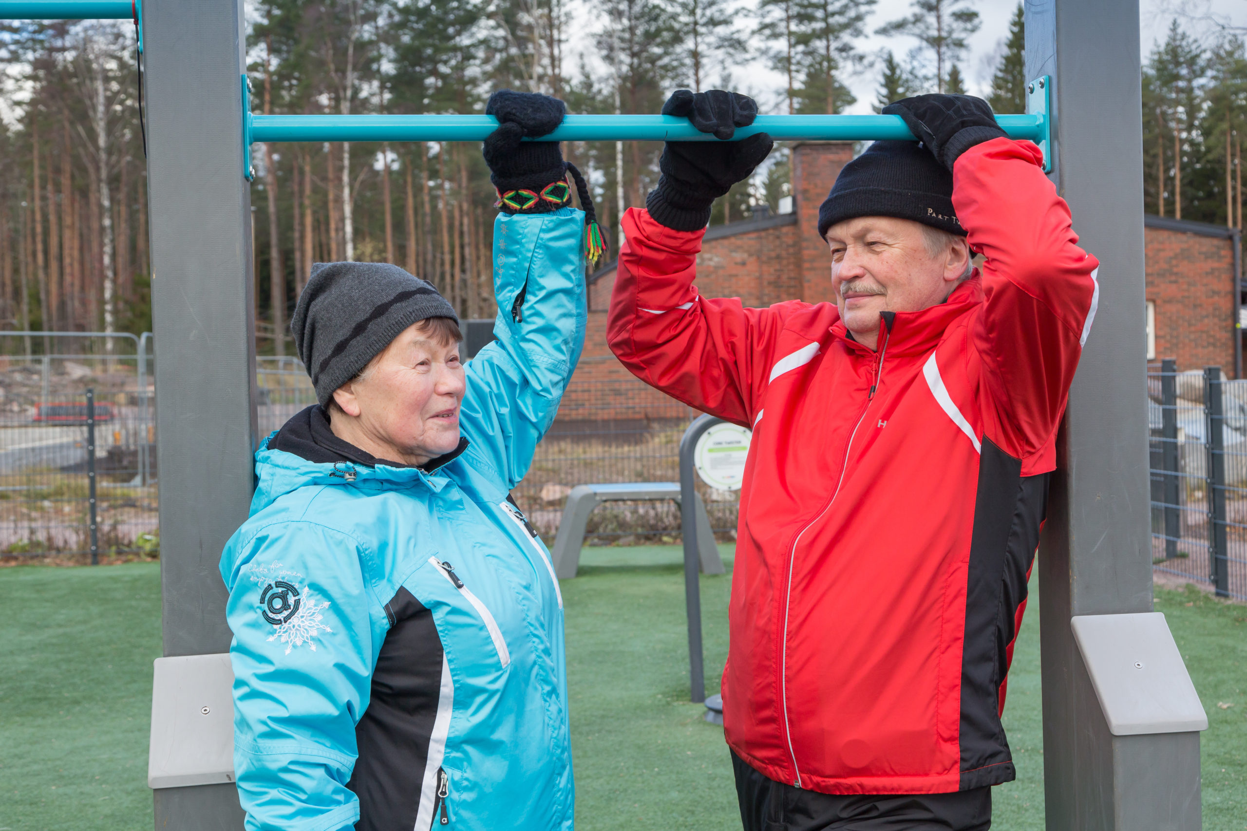 Seniorit kuntoilevat urheilupuistossa ulkona syksyllä.