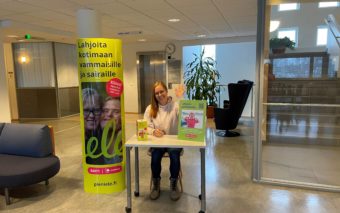 Pieni ele kerää lahjoituksia vammaisille ja pitkäaikaissairaille aluevaalien äänestyspaikoilla. Keräyspisteen iloinen vapaaehtoinen tervehtii käden heilautuksella äänestäjiä.