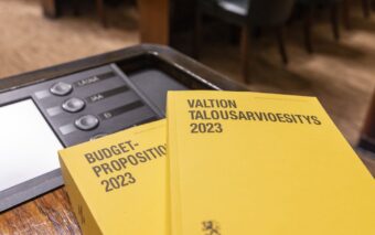 Kaksi valtion vuoden 2023 talousarvioesitystä pöydällä eduskunnan istuntosalissa.