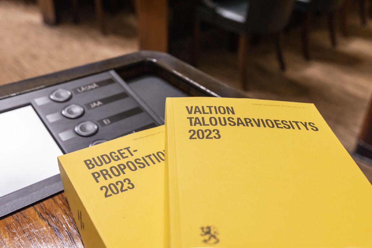 Kaksi valtion vuoden 2023 talousarvioesitystä pöydällä eduskunnan istuntosalissa.