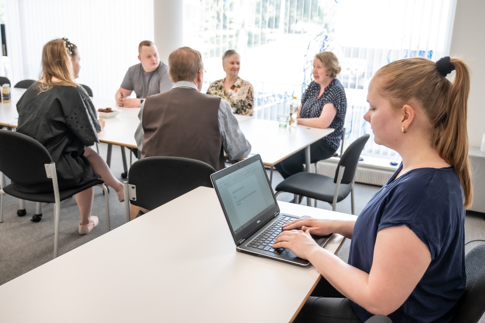 Kokoustilassa viisi ihmistä ja kirjoitustulkki.