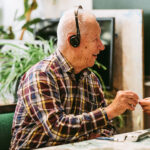 mies kommunikaattorin kuulokkeet korvilla hymyilee.