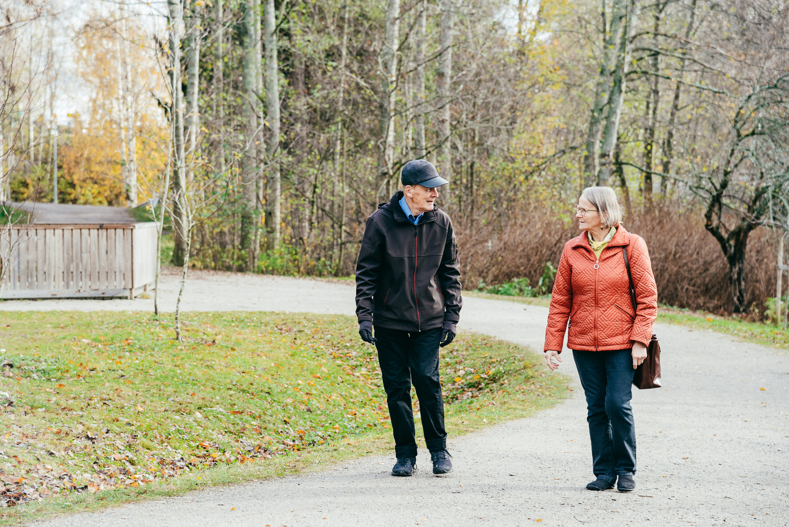 nainen ja mies kävelevät syksyisessä puistossa toisiinsa katsoen