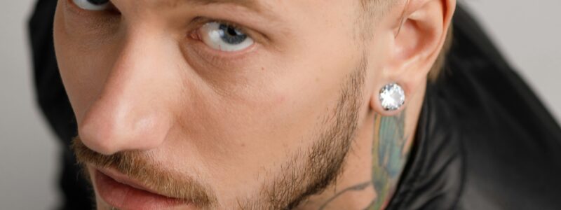 mies katsoo kameraan, korvassa korvis.