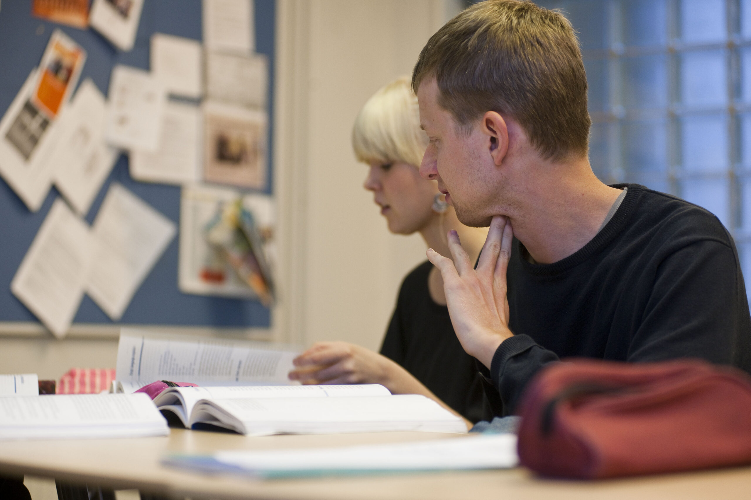 mies ja nainen katsovat kirjaa pöydän ääressä.